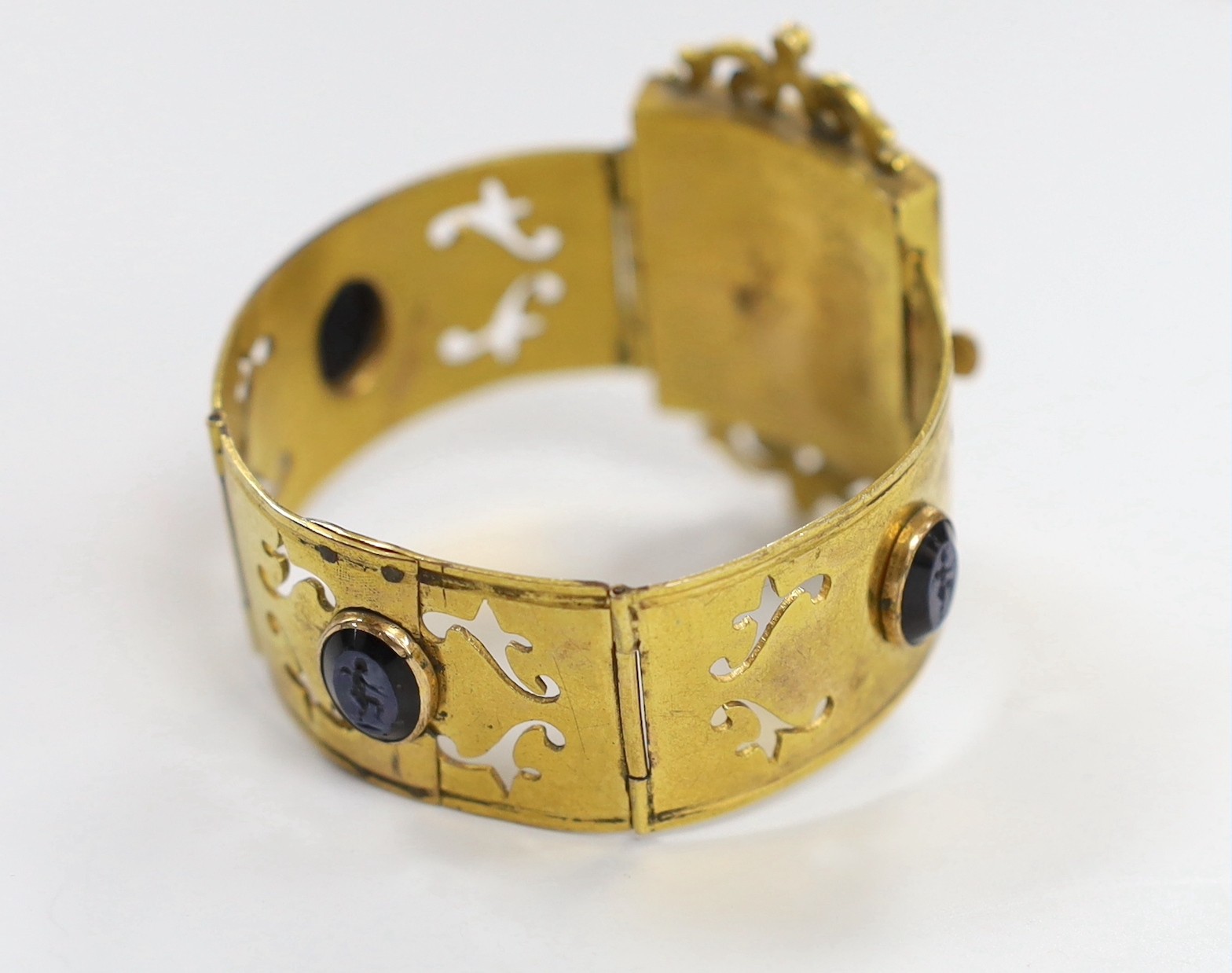 A Victorian gilt metal and four stone glass intaglio set bracelet, (repair), each stone carved with a cherub, 15cm.